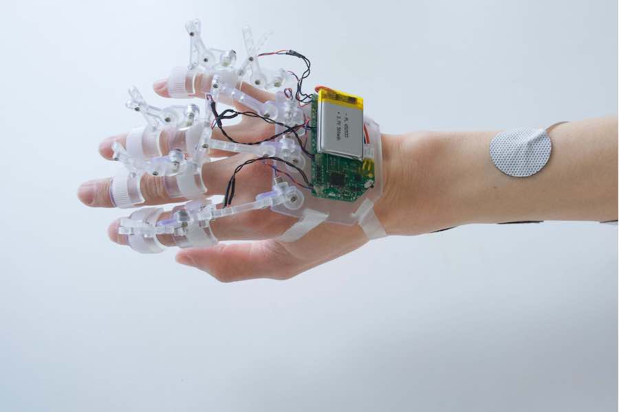 DextrEMS, a wearable device combining electrical muscle stimulation and mechanical brakes to control individual fingers.