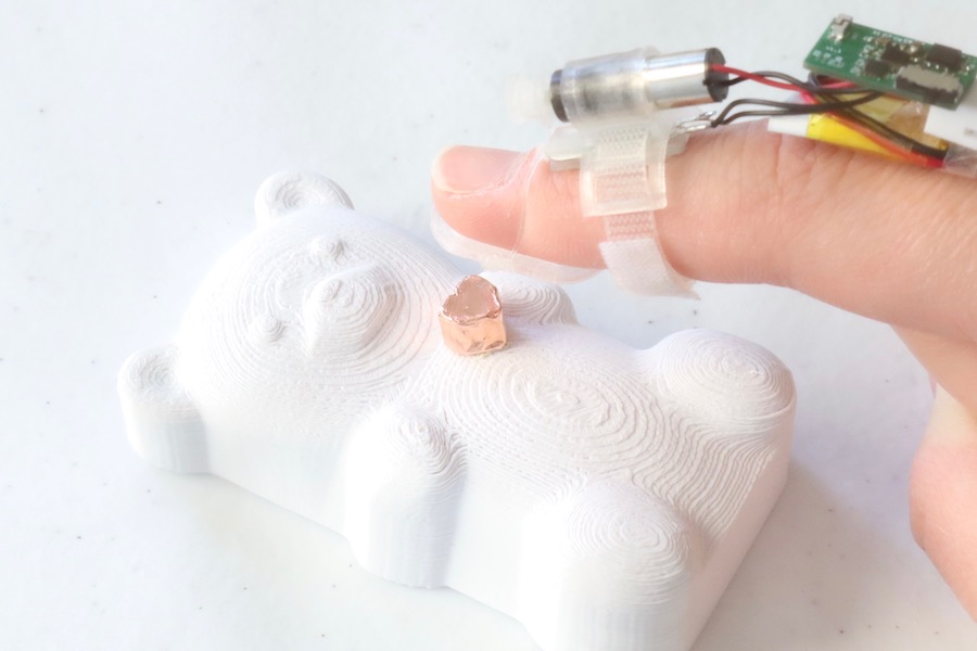 A user wearing the fingerpad device touches a 3D-printed teddy bear made from rigid material. (Photo by Yujie Tao)